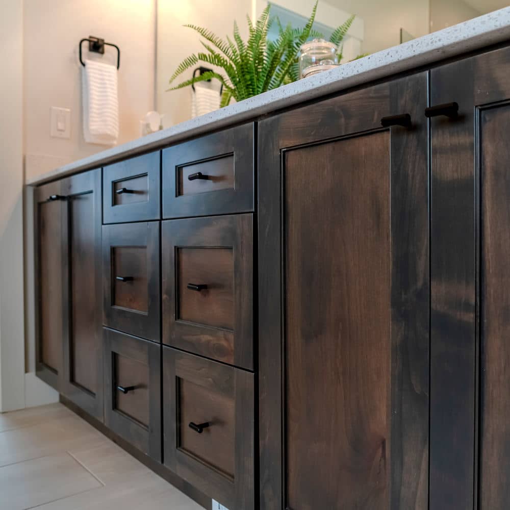 Brown wooden vanity bathroom cabinets with white countertop and black handles